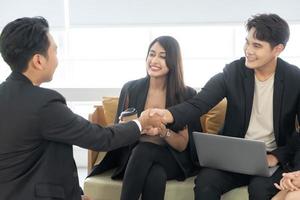 Welcome to our team. young modern men and woman in smart casual wear shaking hands. Three smiling businesspeople shaking hands together. photo