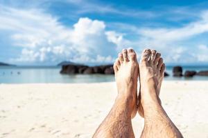 2 feet on the bleach. Close up of young man feet on a tropical sandy beach. photo