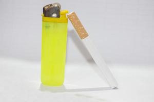un encendedor amarillo y un cigarrillo sobre un fondo blanco. foto