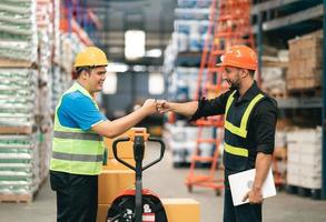 Manager man and factory workers or engineer fist hand bump for agreement or success at works in warehouse storage.Warehouse workers having fun and fist bumping during beginning start working. photo