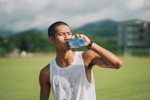 sport man hold bottle water runner tired and thirsty after running workout drinking water. Sport man concept. photo