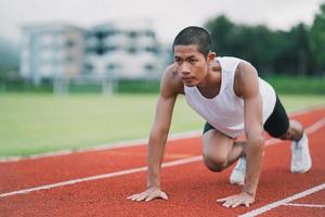 Athletes sport man runner wearing white sportswear to stretching and warm up before practicing on a running track at a stadium. Runner sport concept. photo