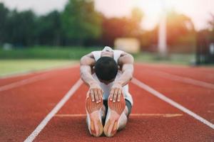 atletas deportistas corredores con ropa deportiva blanca para estirarse y calentarse antes de practicar en una pista de atletismo en un estadio. concepto de deporte de corredor. foto