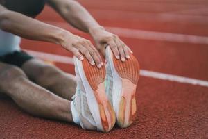 Athletes sport man runner wearing white sportswear to stretching and warm up before practicing on a running track at a stadium. Runner sport concept. photo