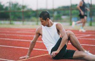 Athletes sport man runner wearing white sportswear to stretching and warm up before practicing on a running track at a stadium. Runner sport concept. photo