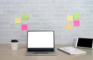 vista de cerca de la mesa de trabajo con computadora portátil o computadora, tableta, computadora portátil, bolígrafo y nota post-it en la sala de la oficina en casa. trabajo en casa en el concepto de sala de estar. foto