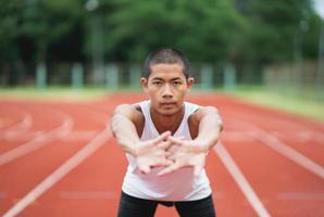 Athletes sport man runner wearing white sportswear to stretching and warm up before practicing on a running track at a stadium. Runner sport concept. photo