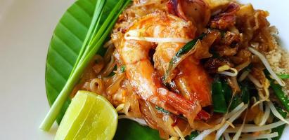 Close up stir fried with rice noodle, river prawn or shrimp, bean sprout, sliced chives and lime on banana leaf with copy space. Famous food in Thailand call Pad Thai. Selective focus technique. photo