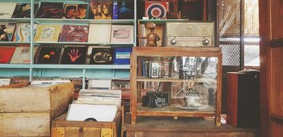 Samut Sakhon, Thailand  July 15 2022 Many record or dish put on wooden shelf for sale. Collection group of vintage object and classic camera in glass cabinet. photo