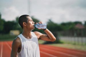 sport man hold bottle water runner tired and thirsty after running workout drinking water. Sport man concept. photo