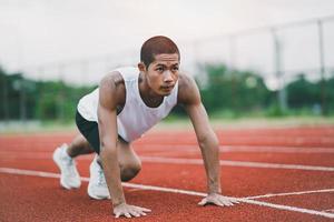 Athletes sport man runner wearing white sportswear to stretching and warm up before practicing on a running track at a stadium. Runner sport concept. photo