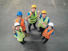 Group of industrial warehouse asian worker in and safety suite celebrating or raise hands pose successful or deal commitment. Logistics , supply chain and warehouse business. Teamwork unity Top view.