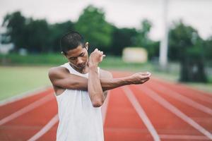 Athletes sport man runner wearing white sportswear to stretching and warm up before practicing on a running track at a stadium. Runner sport concept. photo