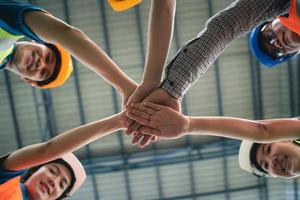 un grupo de trabajadores asiáticos de almacenes industriales y una pila manual de la suite de seguridad celebran un compromiso exitoso o de trato. Logística, cadena de suministro y negocio de almacén. Unidad de trabajo en equipo bajo el concepto de vista. foto