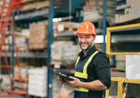 empleado de gerente profesional que usa stock de verificación de tabletas trabajando en el almacén. trabajador con ropa de alta visibilidad y casco, casco y comprobando y contando mercancías o cajas para su entrega. foto