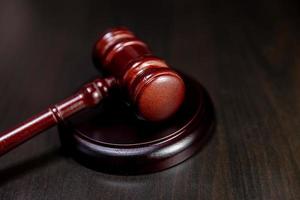 Law theme. Court of law trial in session. Judge gavel on wooden table in lawyer office or court session. Mallet of judge on dark background. Justice human rights concept. photo