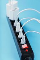 Surge protector with connected white wires of electrical appliances on a blue background. photo