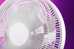 White modern electric fan for cooling the room on a pink background. photo