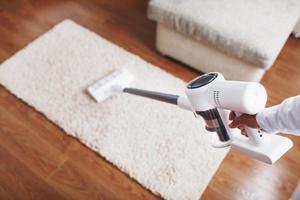 The turbo brush of a cordless vacuum cleaner cleans the carpet in the house in close-up photo