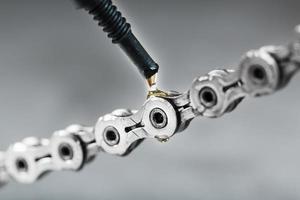 Greasing a bicycle chain with a drop of golden oil close-up on a gray background photo