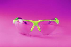 Transparent polycarbonate safety glasses on a pink background photo