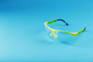 Transparent polycarbonate safety glasses on a blue background. photo