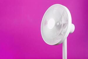 White modern electric fan for cooling the room on a pink background. photo