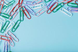 Colored paper clips on a blue background with free space photo