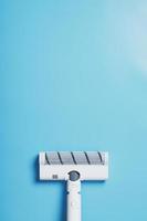 White vacuum cleaner brush on a blue background, top view. Cleaning concept photo