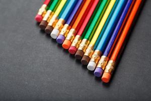 Colorful pencils with erasers in a row on a black background photo