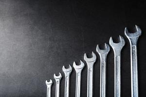 Tool wrenches in a row on a black background with free space.