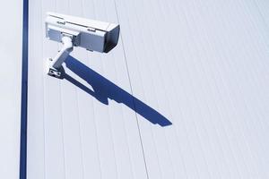 White street surveillance camera on the white wall of the building. photo