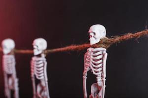 Skeletons hang on a rope on a black background with red illumination