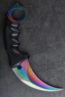 Kerambit dagger with a rainbow-colored blade on a dark textured background. photo