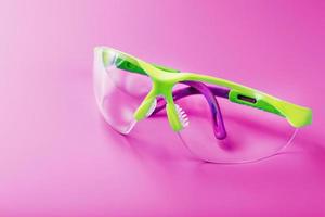 Protective open glasses isolated on a pink background. photo