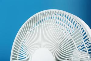 The grille and blades of the electric fan are white on a blue background photo