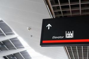 A sign with an arrow pointing to the elevator in the airport waiting terminal. photo