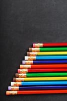 Colorful pencils with erasers in a row on a black background