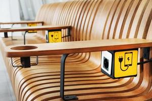 A designer wooden bench with sockets and a yellow sign for charging smartphones in the waiting room. photo