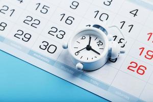 Alarm clock and calendar on a blue background photo