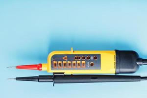 Yellow tester for step-by-step indication of voltage in an electrical circuit on a blue background. photo