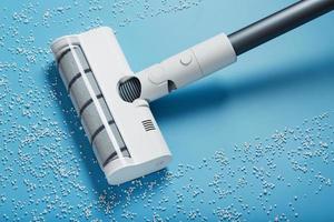 The turbo brush of the vacuum cleaner cleans white balls, top view on a blue background. The concept of cleanliness and cleaning. photo