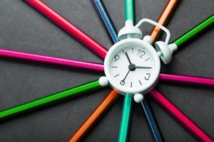 A white alarm clock with colored pencils in the shape of a star photo