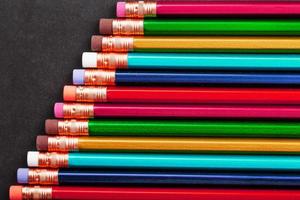 Pencils of different colors in a row on a black textured background. photo