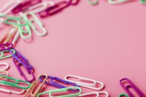 Multicolored rzhivtkzhtsrbt Paper clips scattered on a pink background photo