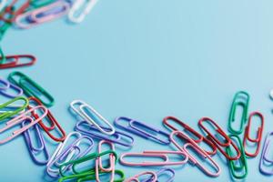 Colored paper clips on a blue background with free space photo