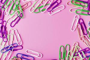Multicolored rzhivtkzhtsrbt Paper clips scattered on a pink background photo