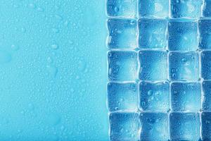 Many frosty and refreshing ice cubes with drops on a blue backgroun photo