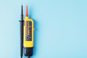 probador amarillo para la indicación paso a paso del voltaje en un circuito eléctrico sobre un fondo azul. foto