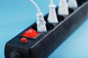 Surge protector with connected white wires of electrical appliances on a blue background. photo